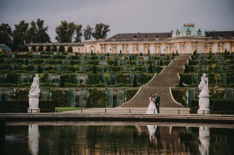 Para młoda na tle tarasów winnych pałacu Sanssouci odbijających się w wodzie